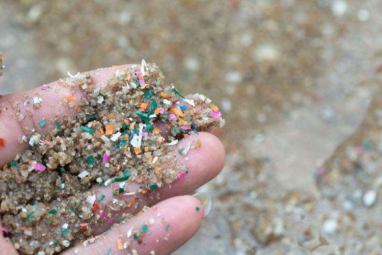  Una mano abierta muestra un puñado de arena cuajado de microplásticos