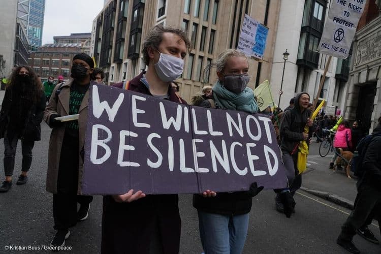 Protester marching with a sign saying "We will not be silenced"