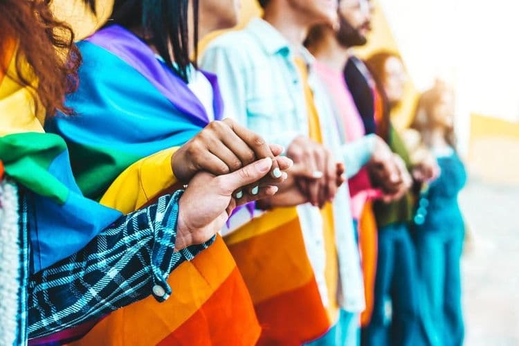 Imagen de personas cogidas de la mano con una bandera LGBTQ+.
