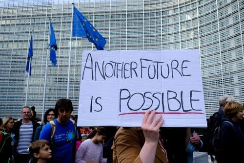 Poster di una manifestazione di fronte alla commissione europea con su scritto "Un altro futuro è possibile"